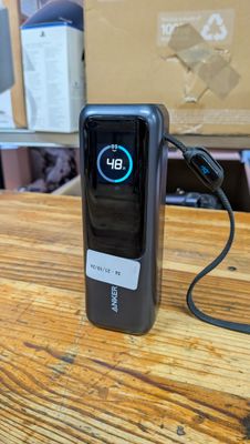 un téléphone portable posé sur une table, branché à un chargeur