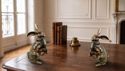 two statues of rabbits sitting on a table in a room