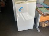 un petit réfrigérateur blanc dans le coin d'une pièce