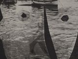 a black and white photo of a man ' s face with boats in the water