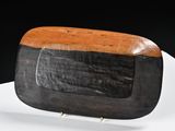 une assiette en bois posée sur une table blanche, sur fond noir
