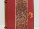 an old book with a red cover and gold trim