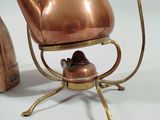 a copper tea pot on a stand with a tea kettle on it