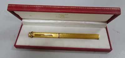 une image représentant un stylo doré dans un coffret rouge posé sur une surface blanche
