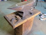 an old anvil sitting on top of a table in a workshop