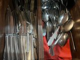 spoons and spoon knives are in a drawer with a red cloth