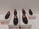 Quatre paires de chaussures noires sont exposées dans une vitrine.