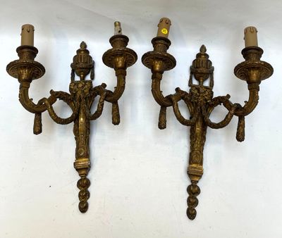 three antique brass wall sconces with candles on each of them