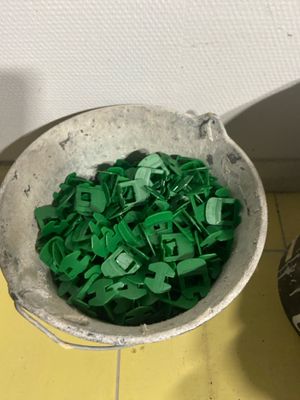 a bucket full of green plastic letters next to a bowl of green plastic letters