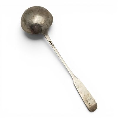 une cuillère en argent avec un manche de cuillère sur une surface blanche