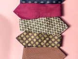 six different colored ties arranged in a row on a pink background