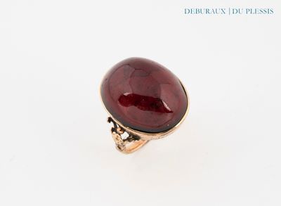 une image représentant une bague en pierre rouge posée sur une surface blanche