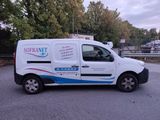 a white van parked in a parking lot with trees in the background