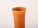 an orange vase sitting on a table with a white background