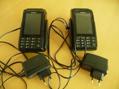 three cell phones sitting on a table with a charger plugged in