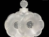 une image représentant un flacon de parfum en verre blanc orné d'une fleur sur le bouchon