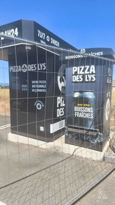 une photo en noir et blanc d'un kiosque de livraison de pizzas au bord de la route