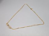 a gold plated necklace with a square clasp on a white surface