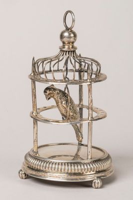 un oiseau en argent dans une cage posée sur un socle