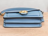 three blue purses stacked on top of each other on a wooden table