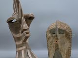 une paire de sculptures en bois représentant une tête d'homme et un visage de femme