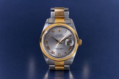 an image of a silver and gold watch on a blue surface