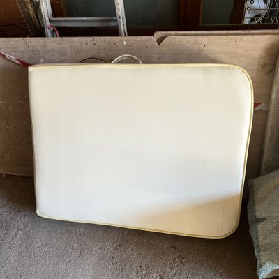 une valise blanche posée par terre à côté d'une chaise