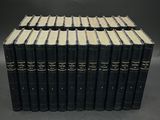 un lot de douze livres reliés en cuir noir, empilés les uns sur les autres