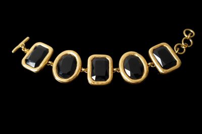 a close up of a black and gold necklace on a black background