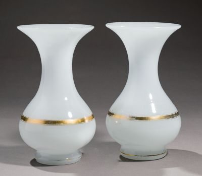 une paire de vases blancs et dorés posés sur une surface grise