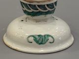 a white and green vase with a green design on it