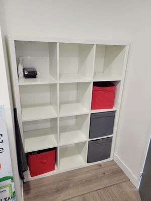 a white bookcase with many different colored bins
