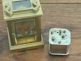 a small clock sitting next to a small box on a table