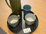 two cups and a pitcher on a tray on a table