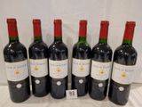 six bottles of red wine are lined up on a table