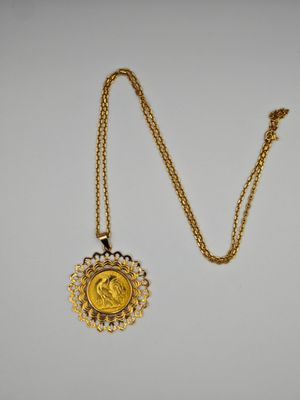 un collier en or avec une pièce de monnaie sur une chaîne