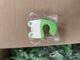 une boîte remplie de bonbons verts et blancs, sur laquelle figure la lettre « d » en vert