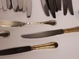 many different types of knives and spoons laid out on a table