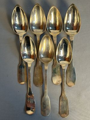 six silver spoons are arranged in a row on a gray surface