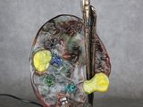statue d'un homme tenant un pinceau et une palette sur laquelle sont posées des billes