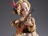an old fashioned doll with a guitar and a feathered hat