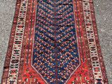a red and blue rug sitting on top of a sidewalk