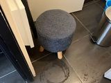 a small stool in the corner of a bathroom next to a trash can