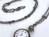 a silver pocket watch on a chain with a chain around it