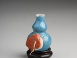 an image of a small blue vase with a leaf on it