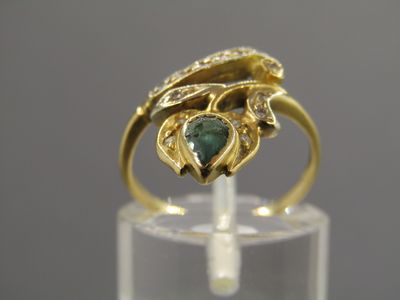 Gros plan sur une bague en or ornée d'une pierre verte