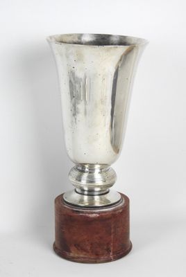 un vase en argent posé sur un socle en bois