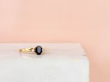 une bague en or sertie d'un diamant noir sur un bloc blanc