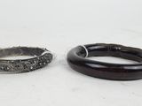 two pieces of silver and black jewelry on a white surface