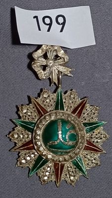 a green and gold medal with a star on it